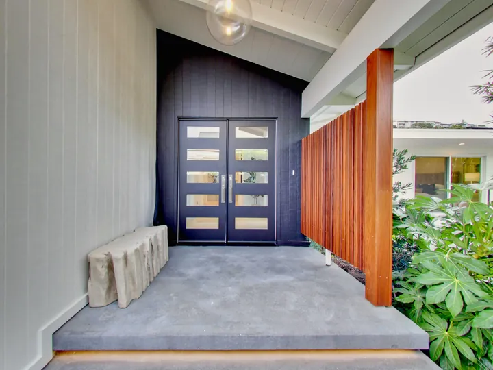 Covered entry with a dark double front door and a redwood slat screen