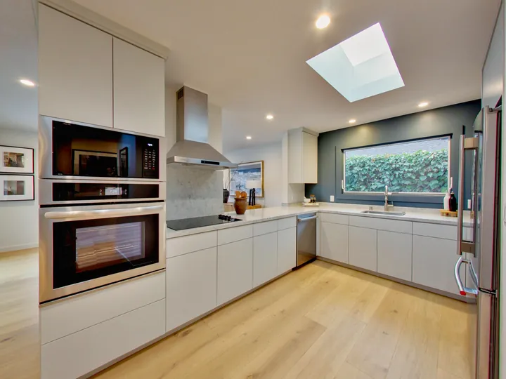 Remodeled kitchen with flat-panel cabinets, wall ovens, a hood and a skylight