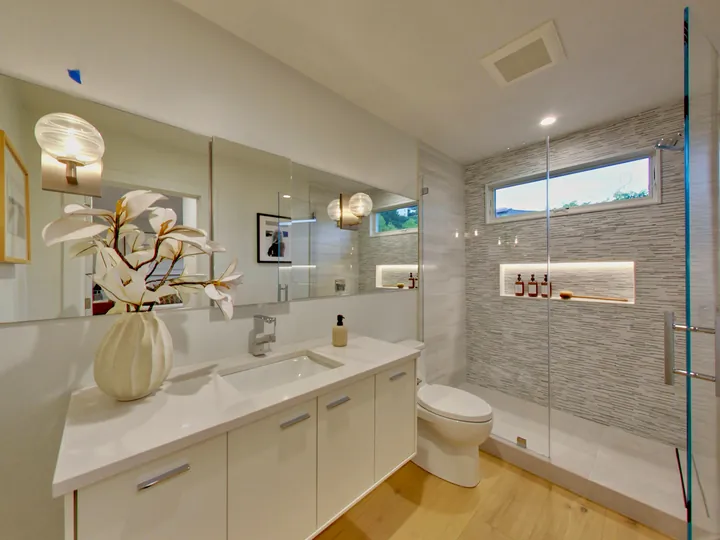 Remodeled primary bathroom with a long vanity and a glass walk-in shower